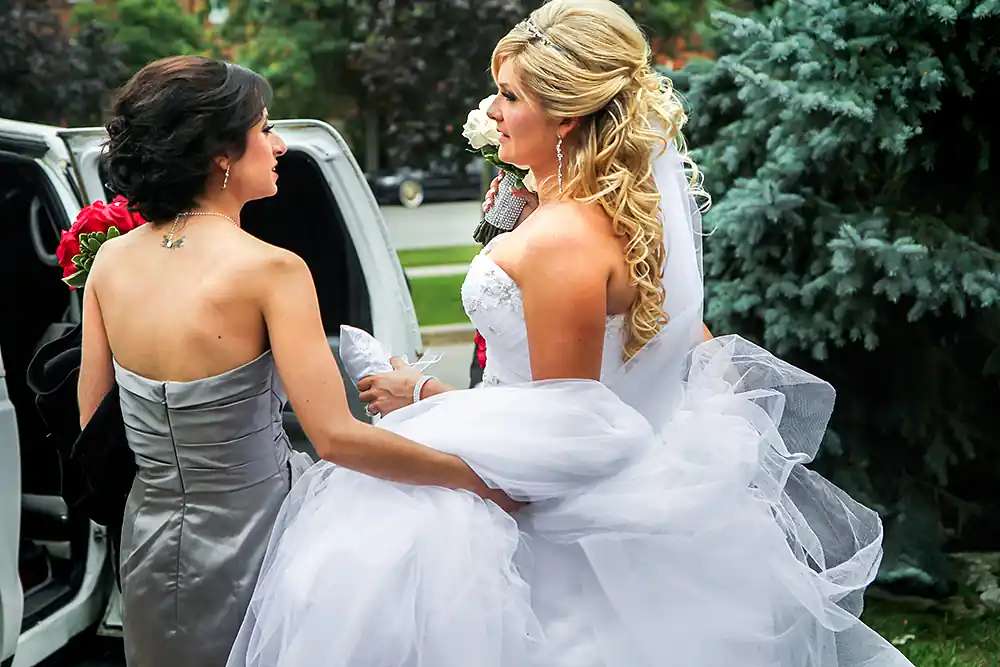 bride and bridesmaid entering an suv limo